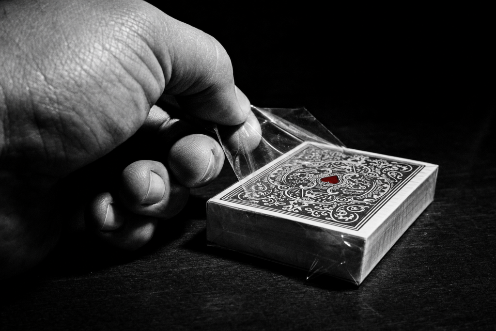 Hand unwrapping a fresh sealed deck of playing cards